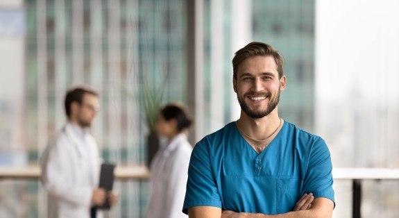 Assistent steht selbstbewusst vor Praxis